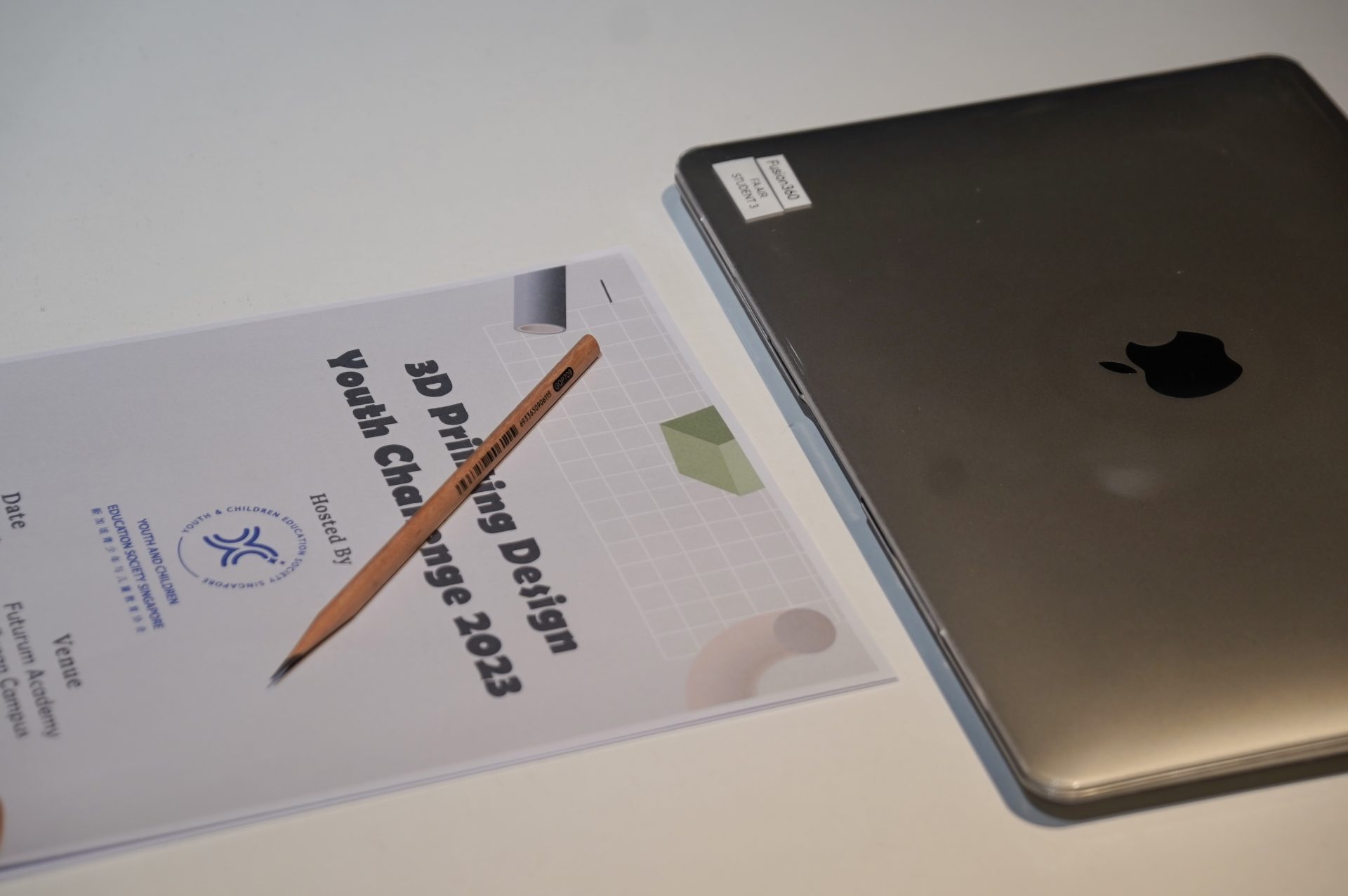 A printed competition brief and a student’s laptop set out before judging